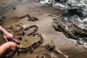 to hender tegner et hjerte på stranden.