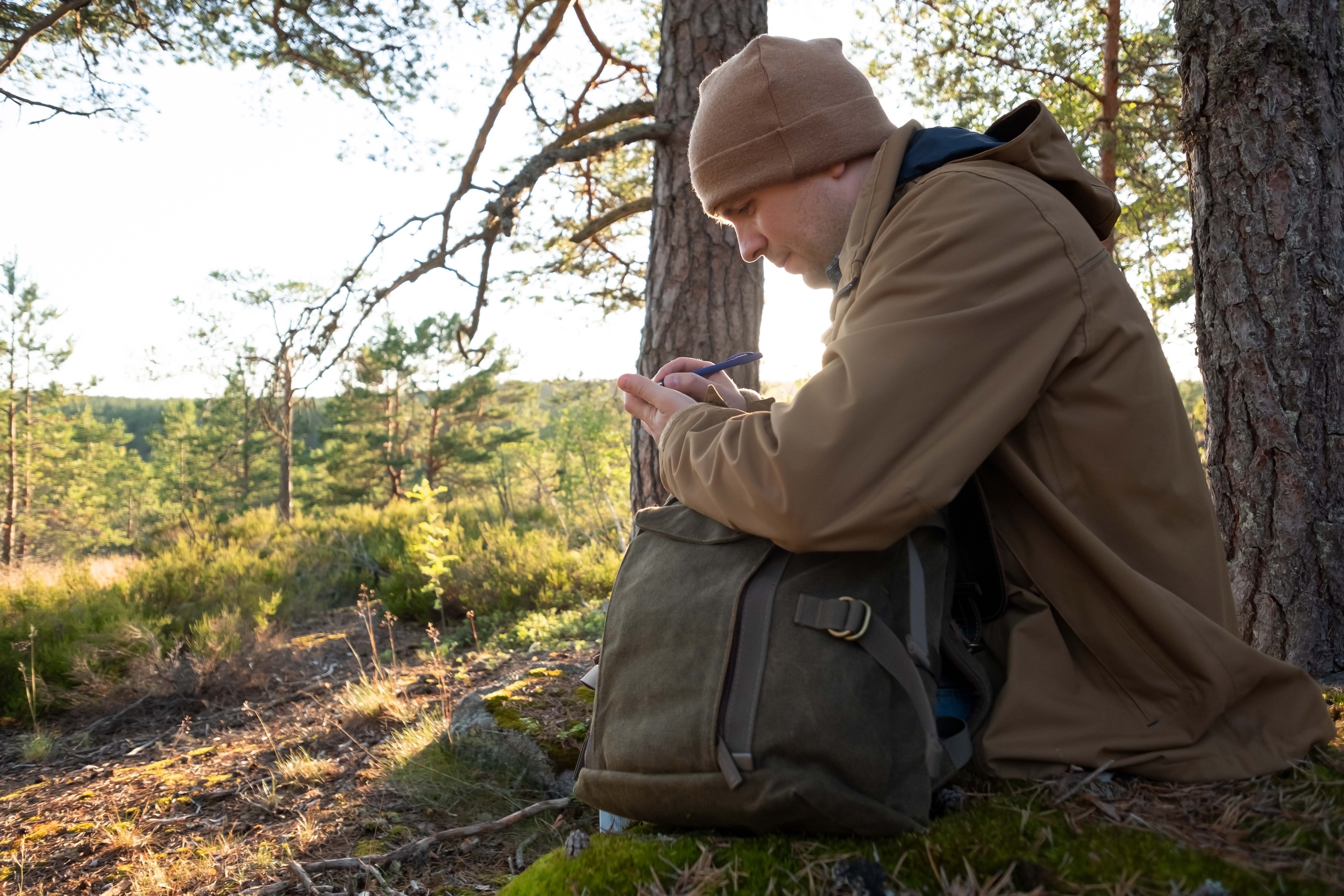 Man sitter ute og skriver ned en refleksjon
