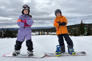 To unge deltakere på Kreftsakens vinterleker øver seg på snowboard